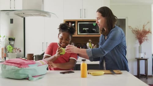 Mother Helping Child Pack School Lunch in Kitchen