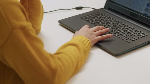 Close-up of hands female scrolling touchpad on a laptop searching on the internet.