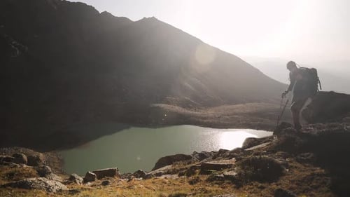 Hiker Tourist with Backpack Walking Near Mountain Lake