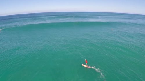 Aerial view of a man sup stand-up paddleboard surfing in Hawaii