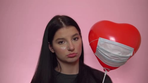Mujer triste con globo en máscara médica