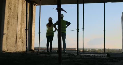 Zwei Chefingenieure mit einer Zeichnung in der Hand beim Blick auf die Baustelle