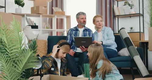 Pareja discutiendo el diseño de habitaciones usando un programa de computadora mientras juguetona con dos niños