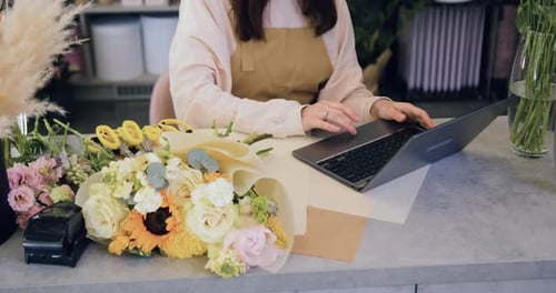 Woman Small Business Owner Working on Laptop in Store Checking Inventory.