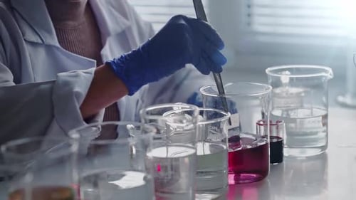 Scientist Adding Sample to Liquid in Beaker