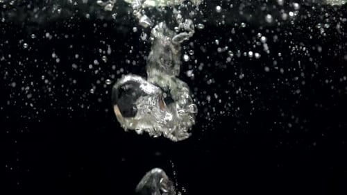 Luftblasen in Zeitlupe im Wasser, die auf schwarzem Hintergrund an die Oberfläche steigen