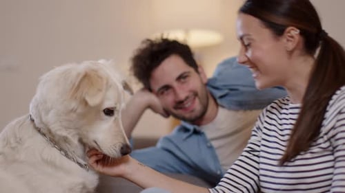 Affectionate Woman Pets Dog with Partner on Couch