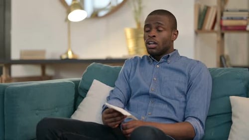 Sick Young African Man Sneezing Sitting on Sofa