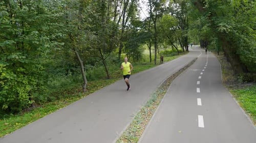 Man Jogging in Park Near Bike Lane