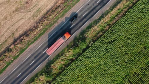Aerial View of Cars and Truck Driving Along a Rural Road Along a Field on a Summer Morning