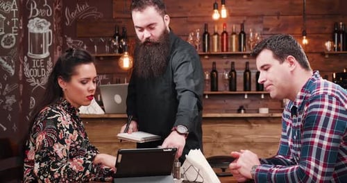 Waiter Takes Order at Cafe from Couple