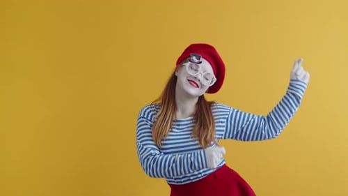 Happy Mime Frau in Baskenmütze und runder Brille tanzt glücklich auf orangefarbenem Hintergrund Konzept von