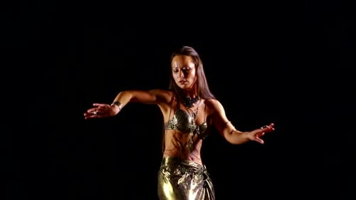 Jeune fille européenne mince dans un costume national oriental dansant sur fond noir danse du ventre