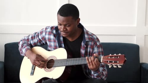 Young Adult Playing an Acoustic Guitar Indoors