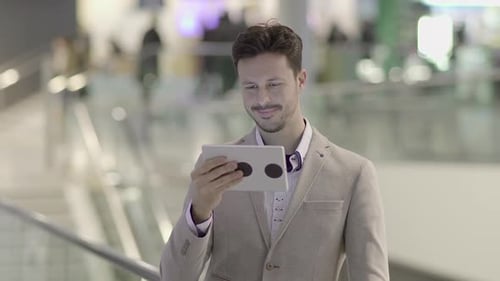 Man Smiling and Using Tablet Indoors