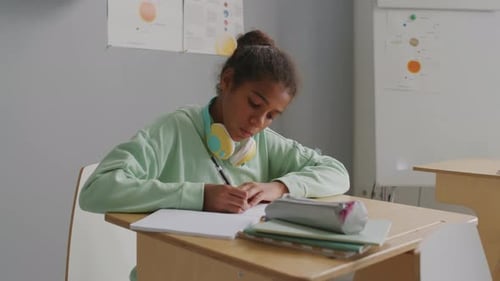 Fille concentrée écrivant dans un carnet pendant la leçon