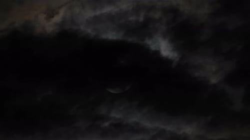 Rising Full Moon Behind the Dark Clouds at Night