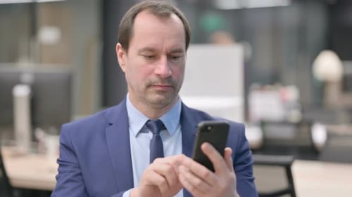Man in Suit Uses Smart Phone in Office