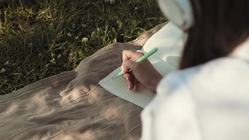 Person Writing in Journal Outdoors