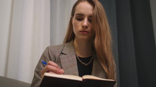 Woman Writes in Notebook Indoors