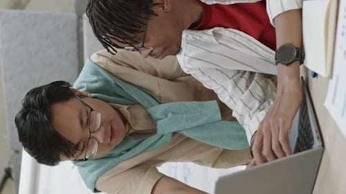 Two Multiethnic Young Men Using Laptop in Office