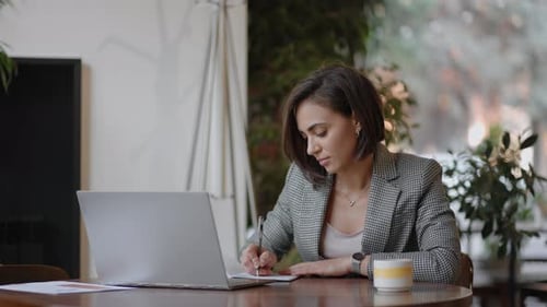 Woman Working at Laptop and Writing Notes