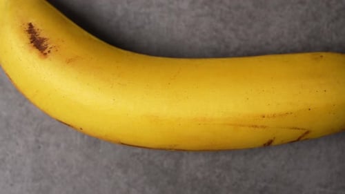 Close Up of Ripe Yellow Banana on Gray Background