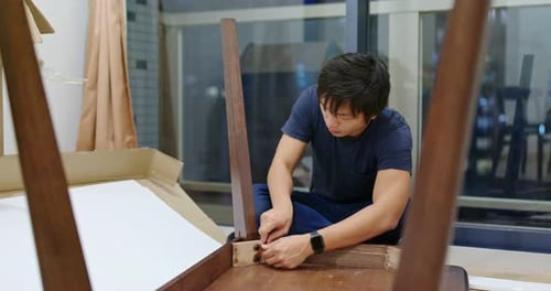 Man Assembling Wooden Table Indoors in Apartment