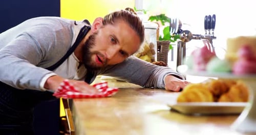 Man Cleaning Counter with Rag in Restaurant