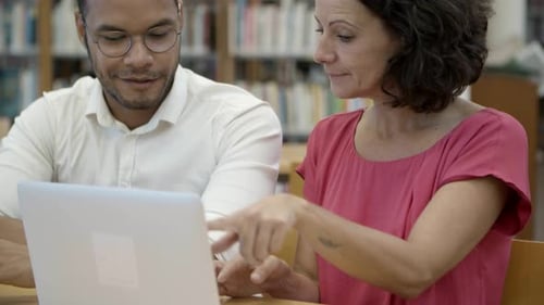 Un étudiant joyeux travaille sur un nouveau projet à la bibliothèque