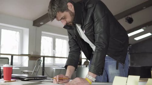 Junger Mann arbeitet an einem Projekt und zeichnet und denkt im modernen Büro