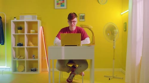 Young Adult Working at Desk in a Yellow Room