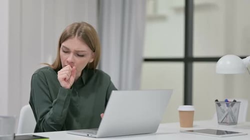 Young Woman Coughing While Using Laptop at Desk
