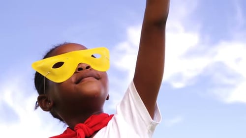 Young Girl Dressed as a Superhero Raises Arm