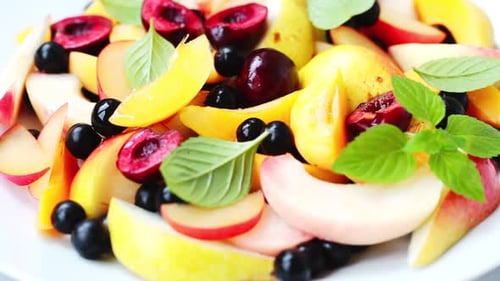 Obstsalat mit Beeren in weißem Teller, weißer Hintergrund.
