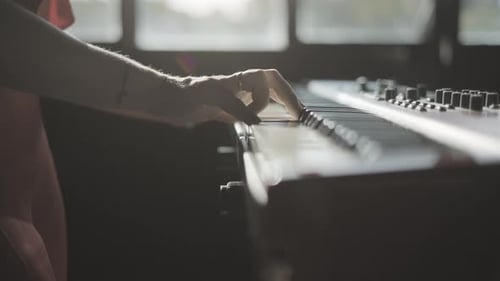 Keyboardist playing electronic piano in dark studio