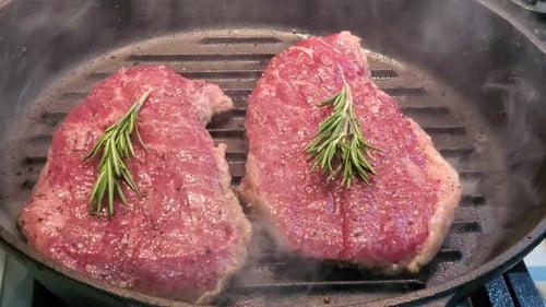 Close-up Video Raw Veal Steak with Rosemary Is Cooked in a Grill Pan