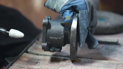 Grinding Metal Part with Gloves in Workplace