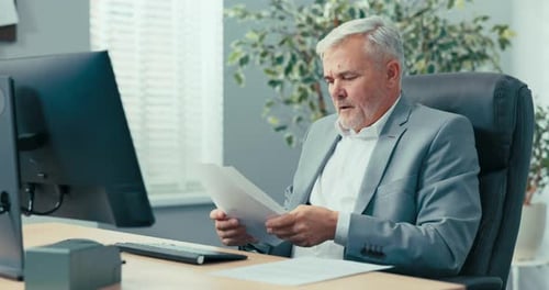 Man Video Conferencing in Office Reviewing Documents