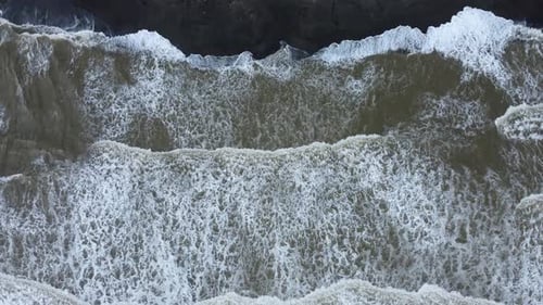 Waves Crashing on Dark Sandy Beach, Aerial View