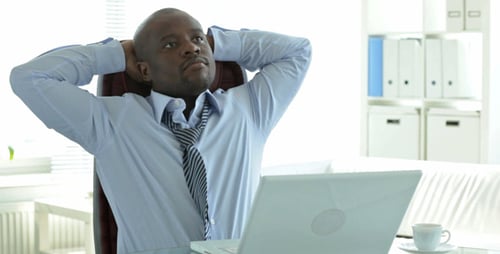 Man Typing on Laptop Then Stretches in Office