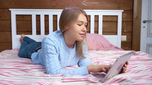 Woman Using Tablet Computer Lying on Bed