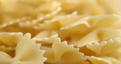 A Bunch of Dry Farfalle Pasta Falls on the Table.