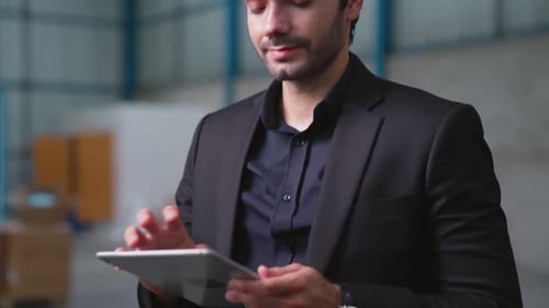 Factory Manager Using Tablet Computer in Warehouse or Factory