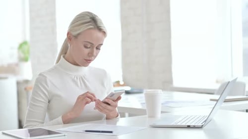 Jeune femme d'affaires utilisant un smartphone au bureau