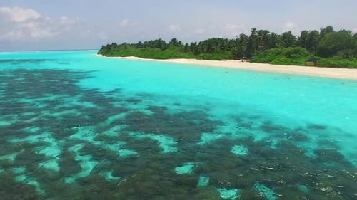 Wide angle panorama of marine island beach break by blue lagoon with sand background near reef
