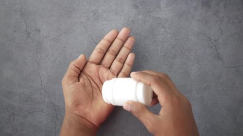Männerhand mit verschütteter Medizin aus dem Pillenbehälter