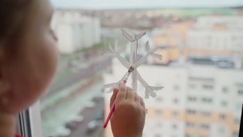 Child draw snowflake on window with paints close-up. Caucasian female person decorate living room