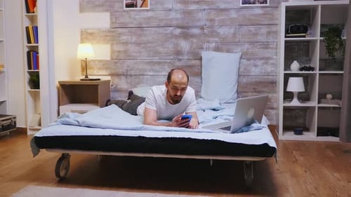 Man on Bed Using Mobile Phone