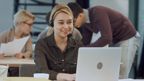 Lächelnde Helpline-Betreiberin mit Kopfhörern an ihr